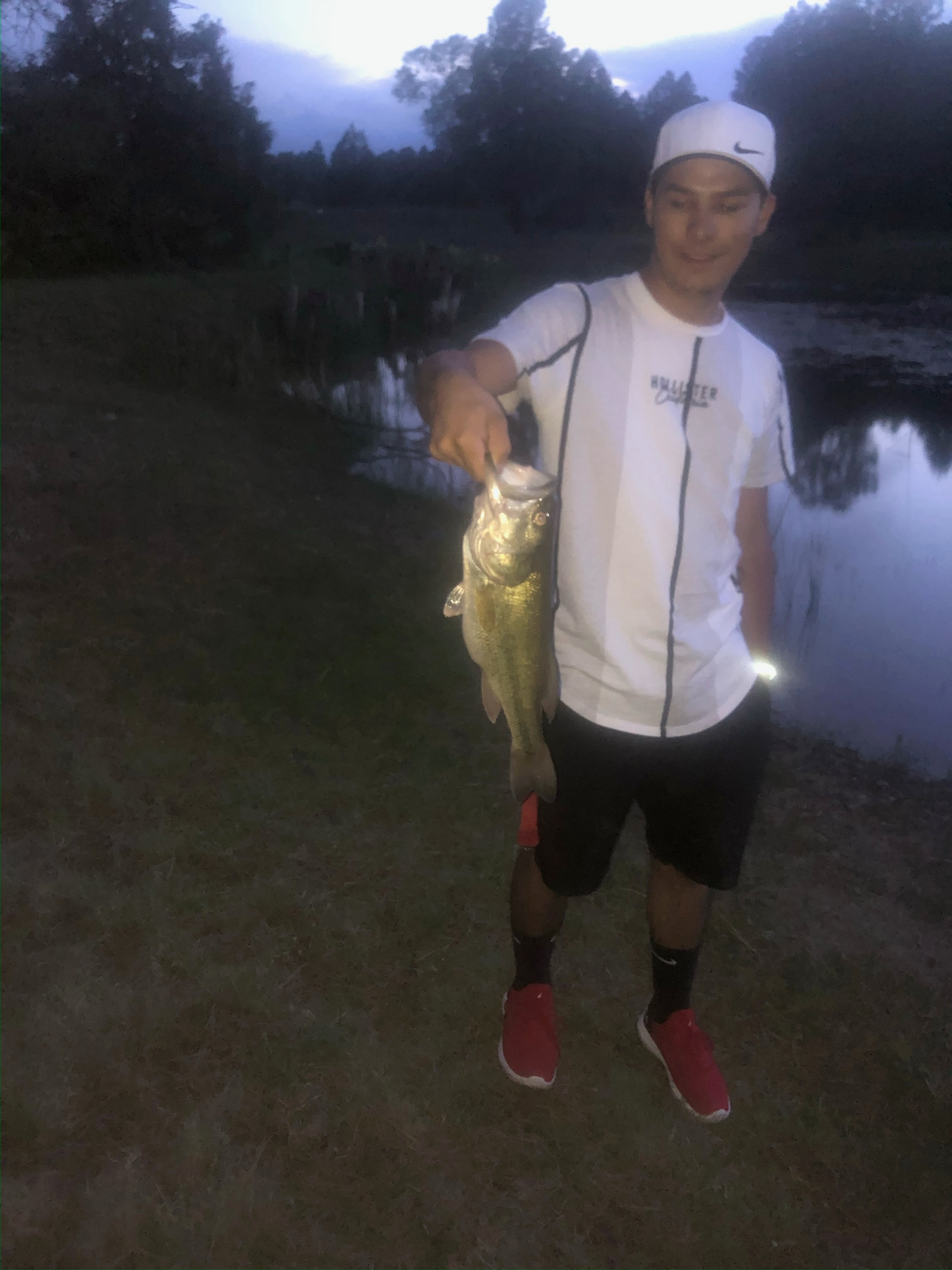 Guest holding a bass caught at the Let-N-Go Ranch pond at night